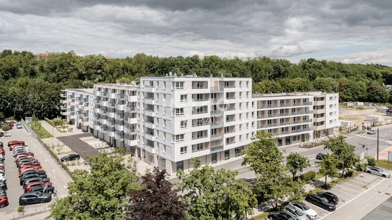 Luftaufnahme eines modernen Wohnkomplexes mit mehreren Gebäuden, Balkonen und umliegenden Parkplätzen.