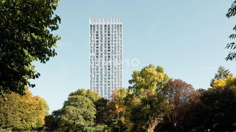Moderner, hoher Wohnturm mit weißer Fassade, umgeben von grünen Bäumen und Natur.