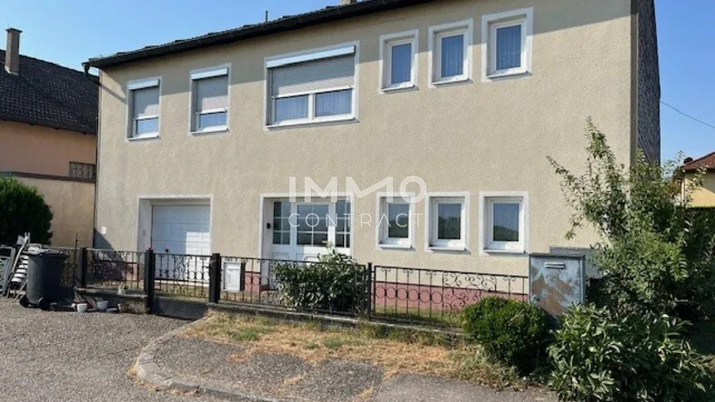 Vorderansicht eines Einfamilienhauses mit Garage, Rollläden und einem kleinen Vorgartenbereich.
