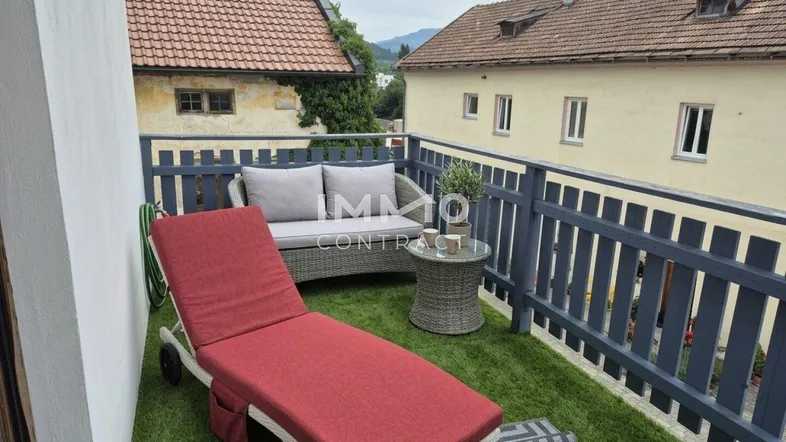 Gemütlicher Balkon mit Kunstrasen, Outdoor-Möbeln und Blick auf die umliegende Landschaft.