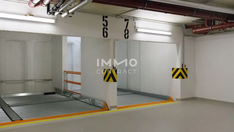 Tiefgarage mit modernen Parksystemen und sichtbaren Installationen an der Decke.