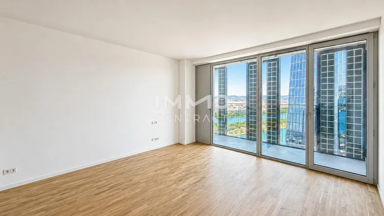 Helles Wohnzimmer mit Parkettboden und großen Fenstern, die einen weiten Blick auf die Stadt und das Wasser bieten.