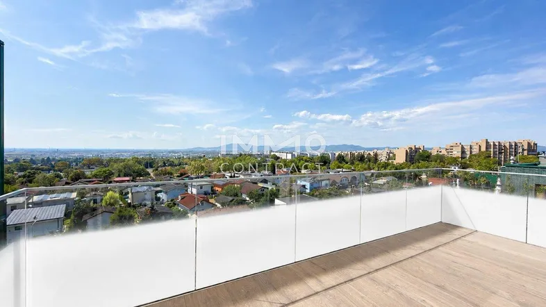 Geräumige Terrasse mit Holzboden und Glasgeländer bietet einen weiten Blick über die Stadt und die umliegende Landschaft.