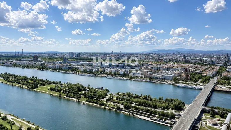 Panoramablick über die Stadt mit Fluss, Brücken und urbaner Landschaft unter blauem Himmel.