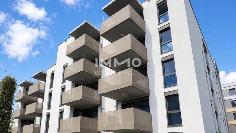 Moderne Wohnanlage mit weißer Fassade und zahlreichen Balkonen unter blauem Himmel.