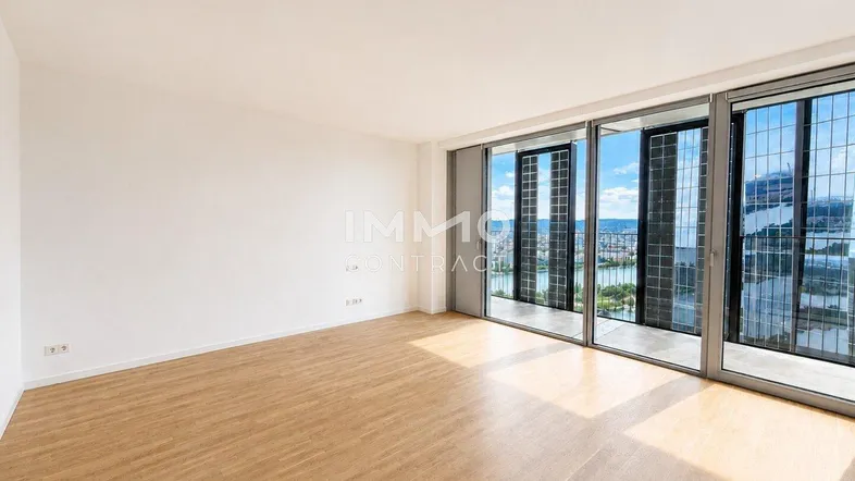 Helles Wohnzimmer mit großen Fenstern, Holzboden und weitem Blick auf die Stadt und das Wasser.