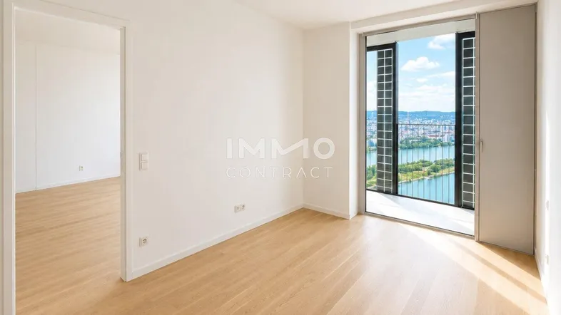 Helles Zimmer mit Holzboden und Zugang zu einem Balkon mit weitem Blick auf den Fluss.
