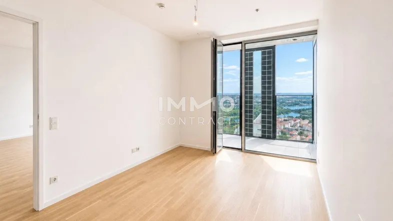Lichtdurchfluteter Raum mit Holzboden und Panoramafenstern mit Blick auf die Stadt.