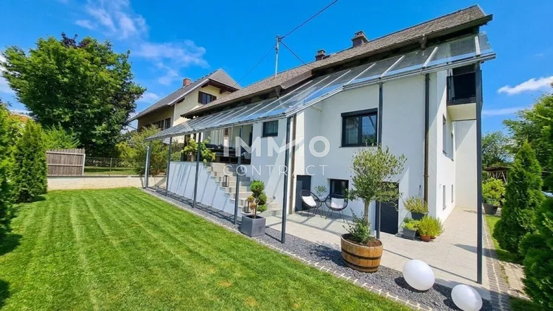 Modernes Einfamilienhaus mit gepflegtem Rasen und überdachtem Terrassenbereich.