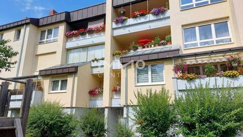 Mehrfamilienhaus mit mehreren Balkonen, die mit bunten Blumenkästen geschmückt sind.