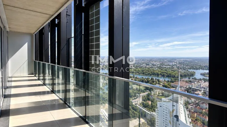 Geräumiger Balkon mit Glasbrüstung und atemberaubendem Panoramablick über die Stadt und den Fluss.