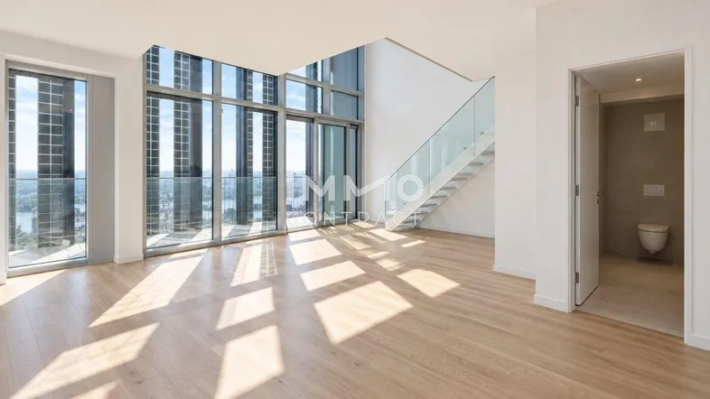 Helles, modernes Wohnzimmer mit hohen Decken, Parkettboden und raumhohen Fenstern mit Stadtblick.