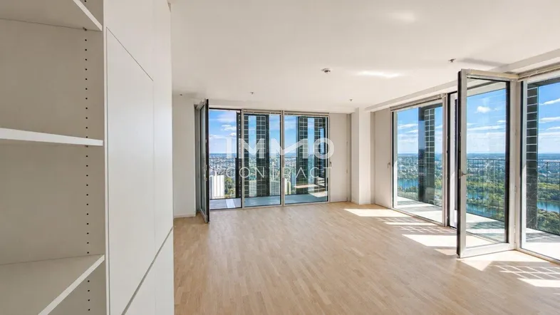 Helles Wohnzimmer mit Holzboden und raumhohen Fenstern, die einen weiten Blick bieten.