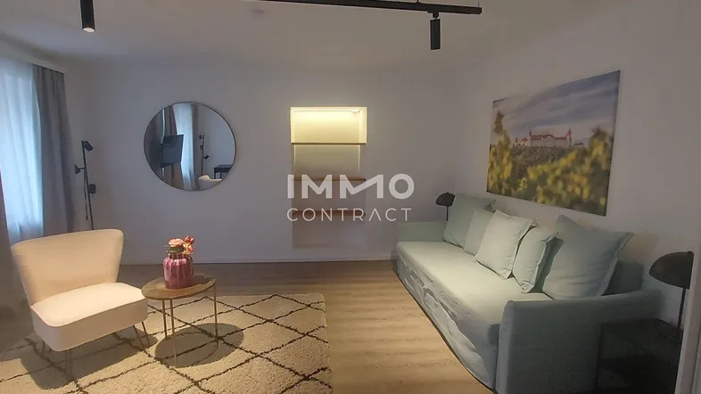 Helles Wohnzimmer mit modernem Sofa, gemütlichem Sessel und dekorativem Wandspiegel.