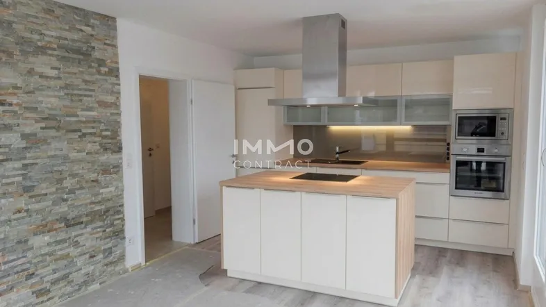 Moderne Küche mit Kücheninsel, integrierten Geräten und einer dekorativen Steinwand.