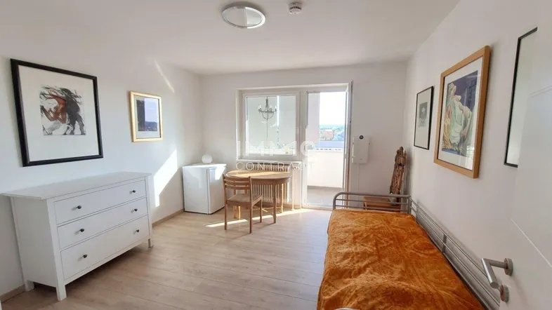 Helles Schlafzimmer mit Holzboden, einem Bett, Kommode und Zugang zu einem Balkon.