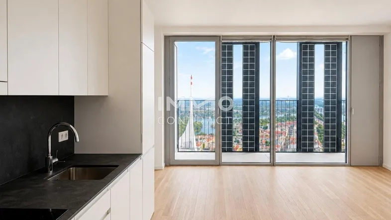 Moderne offene Küche mit hellen Schränken, dunkler Arbeitsplatte und weitem Stadtblick.