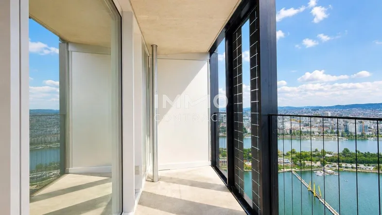 Geräumiger Balkon mit weitem Blick auf den Fluss und die Stadtlandschaft unter blauem Himmel.