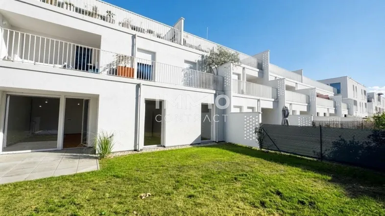 Moderne Wohnanlage mit weißer Fassade, privatem Garten und Terrasse im Erdgeschoss.