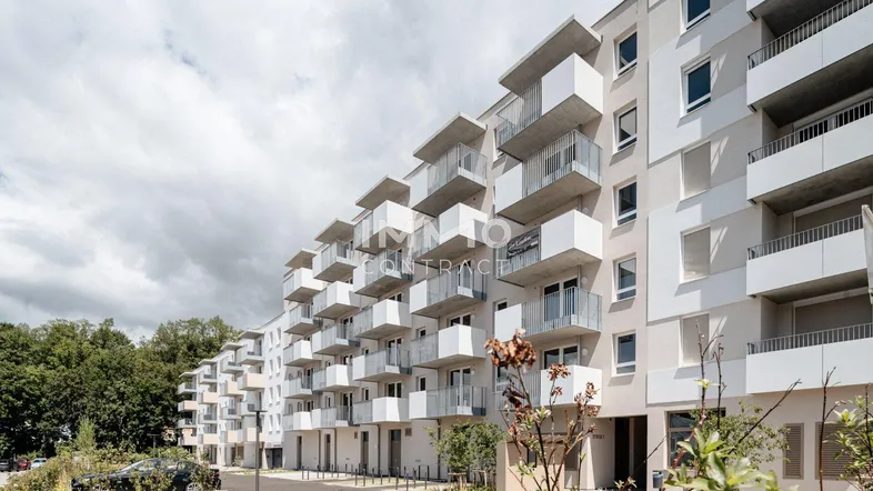 Moderne Wohnanlage mit zahlreichen Balkonen und großen Fenstern, umgeben von Grünflächen.