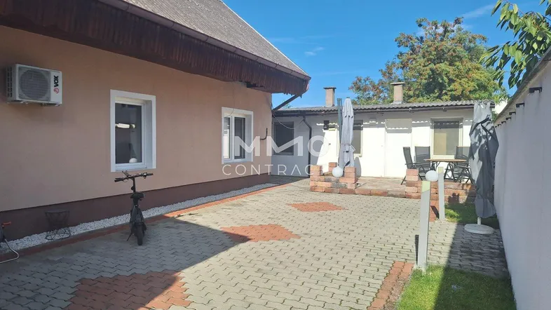 Gepflasterter Außenbereich mit Sitzgelegenheiten und Klimaanlage an der Hauswand.