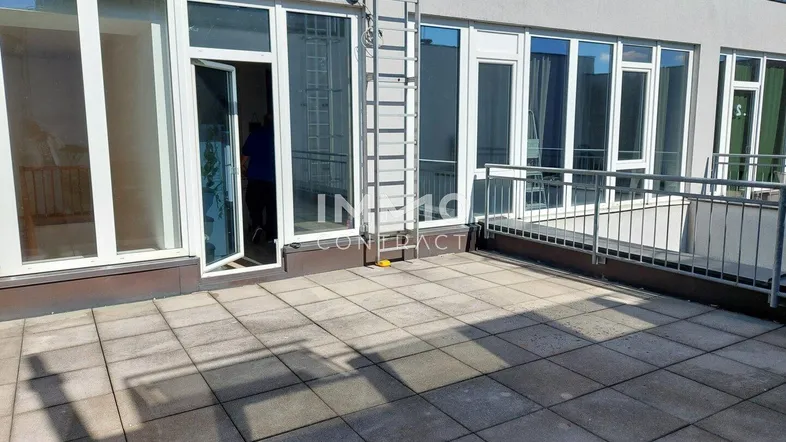 Große, geflieste Terrasse mit Zugang zu den Innenräumen und einer Leiter für Wartungsarbeiten.