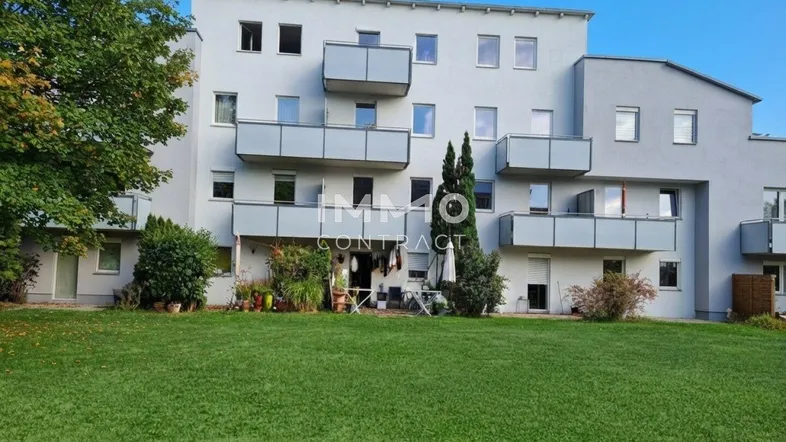 Mehrfamilienhaus mit mehreren Balkonen und einer gepflegten Grünfläche davor.