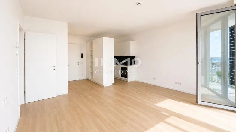Helles Wohnzimmer mit Holzboden und Zugang zu einem Balkon, der einen weiten Blick bietet.