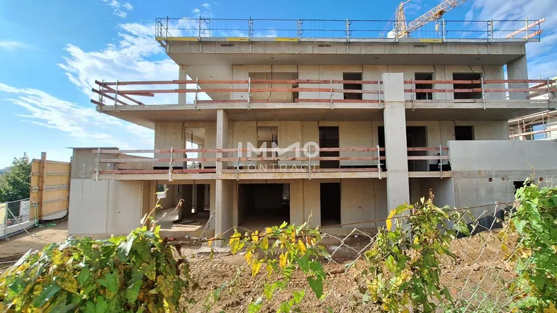 Neubau in Rohbauphase mit mehreren Etagen und sichtbaren Betonstrukturen unter blauem Himmel.