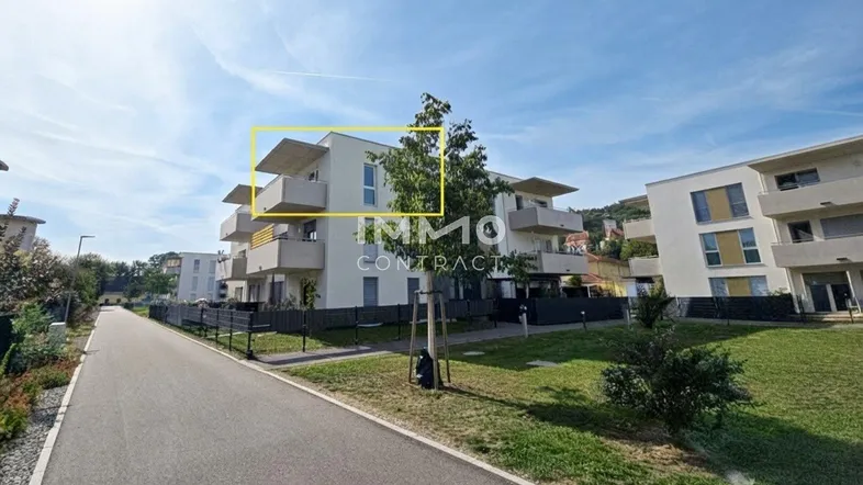 Modernes Mehrfamilienhaus mit Balkonen und gepflegter Grünanlage in sonniger Umgebung.