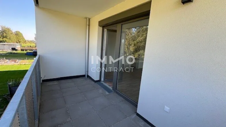 Moderner Balkon mit Fliesenboden und Blick ins Grüne, ideal für entspannte Stunden im Freien.