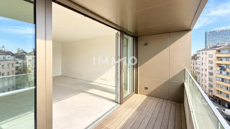 Geräumiger Balkon mit Holzboden und Glasgeländer, bietet einen weiten Blick über die Stadt.