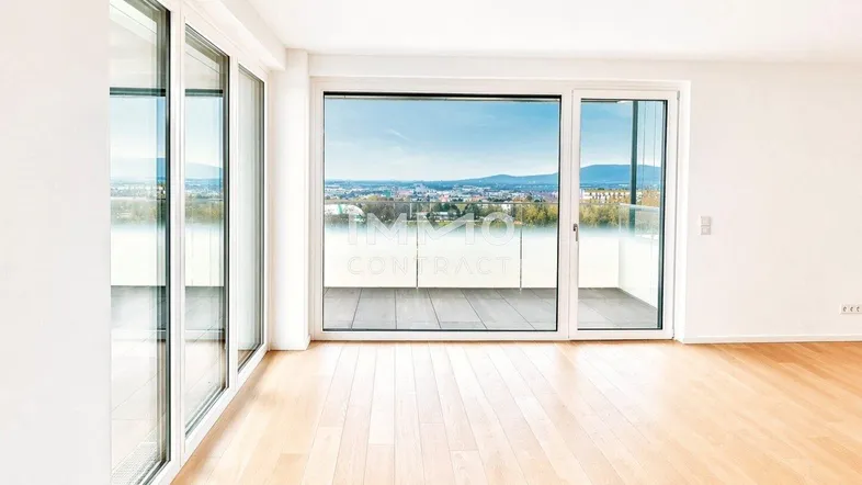 Helles Wohnzimmer mit großen Fenstern, Holzboden und weitem Stadtblick.