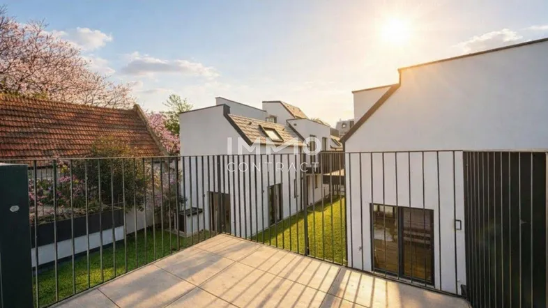 Sonniger Balkon mit Fliesenboden und Blick auf moderne Reihenhäuser sowie einen grünen Garten.