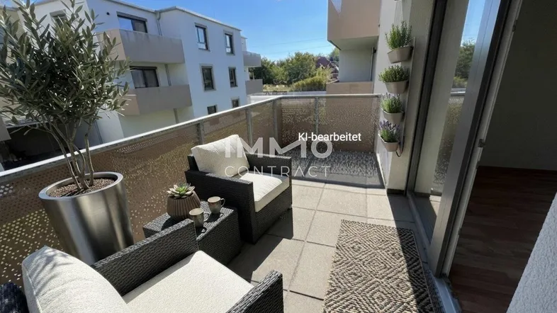 Möblierter Balkon mit Sitzgelegenheiten und Blick auf die umliegenden Gebäude und Grünflächen.