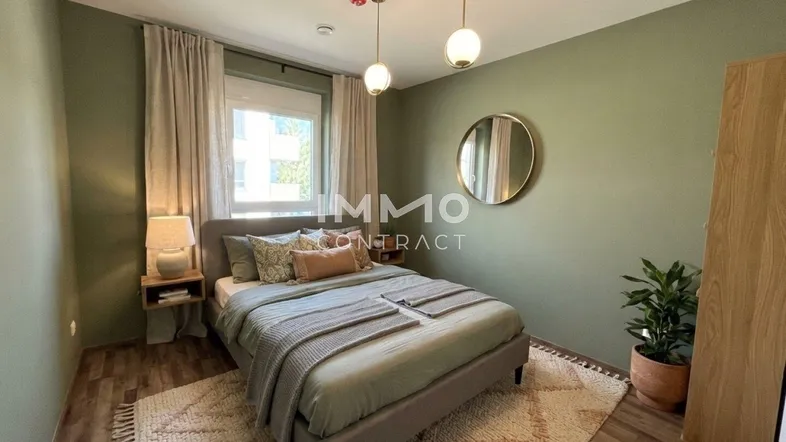 Gemütliches Schlafzimmer mit grün gestrichenen Wänden, einem bequemen Bett und einem runden Spiegel.
