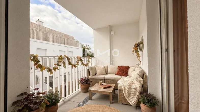 Gemütlicher Balkon mit Rattanmöbeln und Pflanzen, ideal zum Entspannen im Freien.