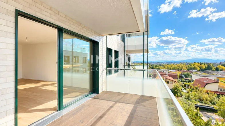 Geräumiger Balkon mit Holzboden und Glasgeländer, bietet einen weiten Blick über die Stadt und die Landschaft.