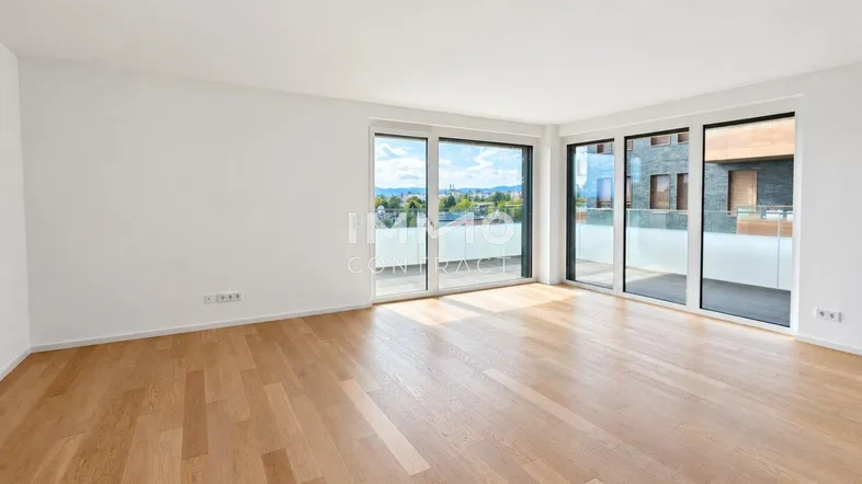 Helles Wohnzimmer mit Holzboden, großen Fenstern und Zugang zu einem Balkon mit Weitblick.