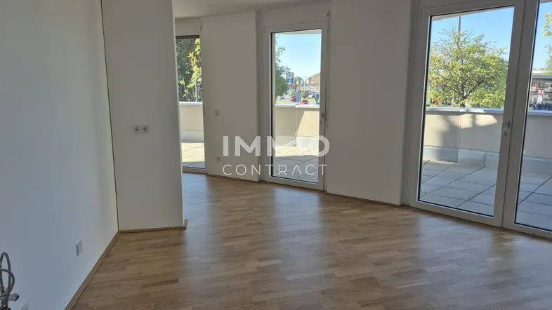 Heller Raum mit Parkettboden und mehreren Zugängen zu einem Außenbereich, ideal als Wohnzimmer.