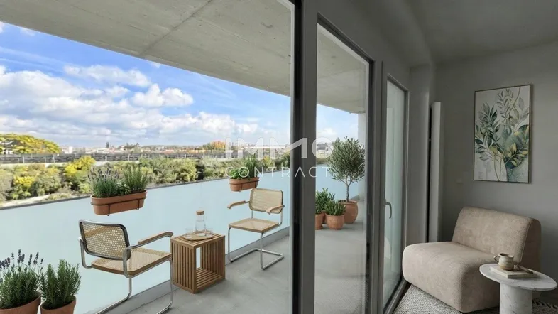 Heller Balkon mit modernen Möbeln, Pflanzen und weitem Blick über die Stadt und viel Grün.
