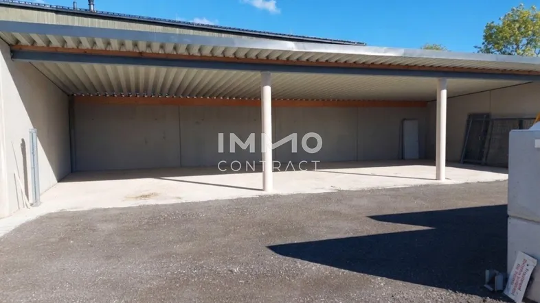 Überdachter Parkplatz oder Lagerbereich mit Betonboden und Metallkonstruktion unter blauem Himmel.