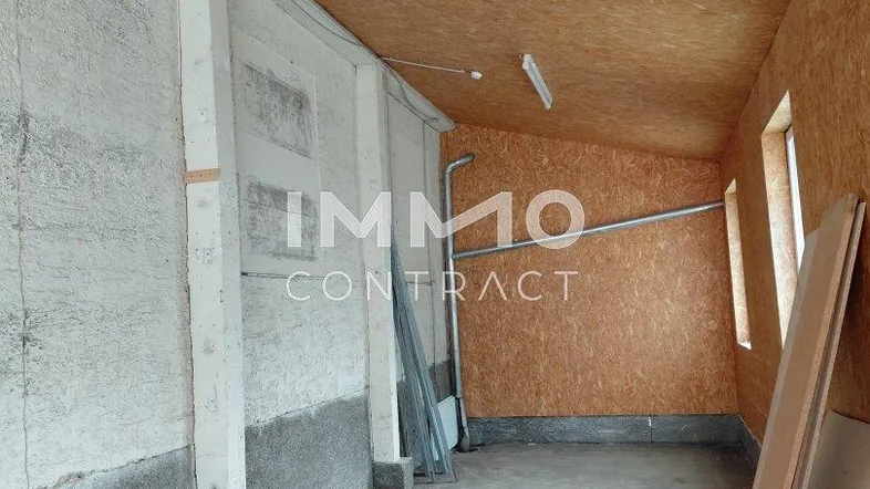 Unfertiger Innenraum mit Betonwänden, OSB-Platten an Decke und Wand, sowie einem Betonboden.