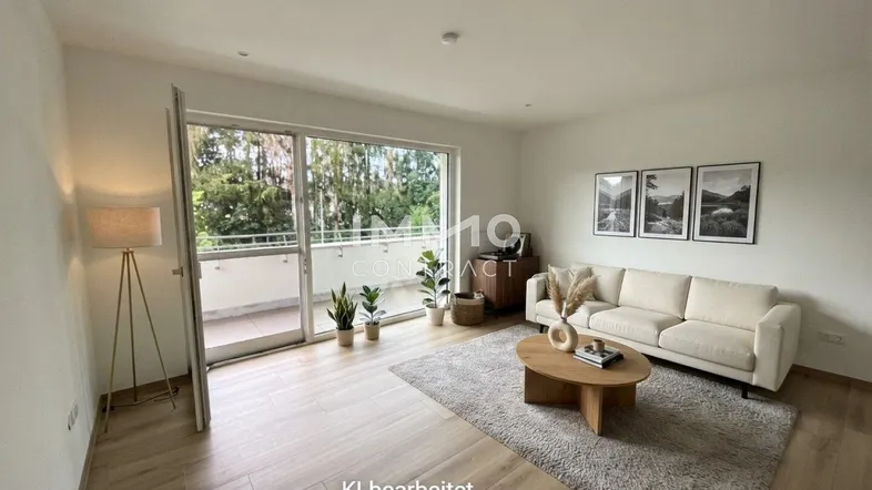 Helles Wohnzimmer mit modernem Sofa, Holzboden und Zugang zu einem Balkon, der viel Tageslicht hereinlässt.