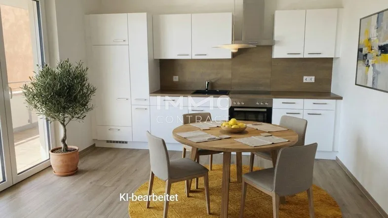 Moderne, helle Küche mit weißen Schränken, Essbereich und Zugang zum Balkon.