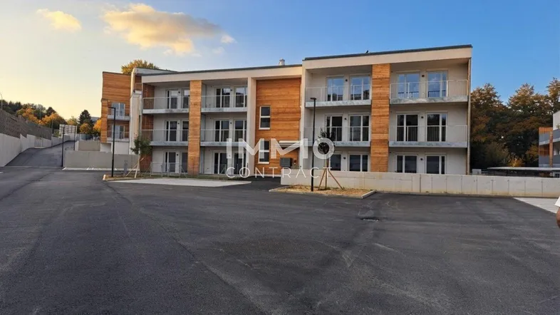 Modernes Mehrfamilienhaus mit Holzfassade und Balkonen in einer Wohnanlage.