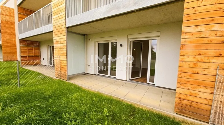 Große Terrasse im Erdgeschoss mit direktem Zugang zur Grünfläche und moderner Holzfassade.