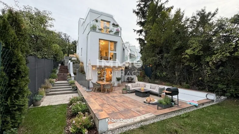 Moderne Reihenhausfassade mit großer möblierter Terrasse und Gartenbereich am Abend.