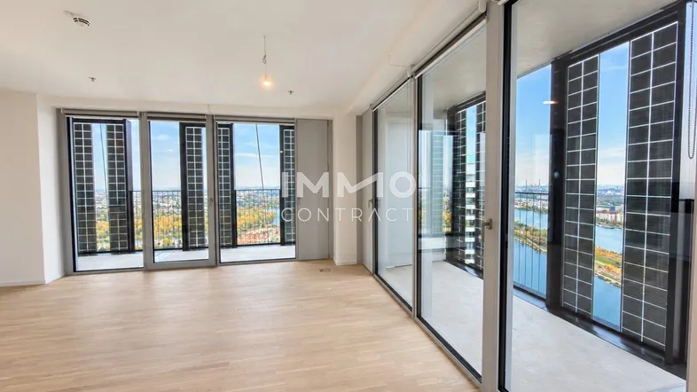 Helles Wohnzimmer mit Holzboden und großen Fenstern, die einen weiten Blick auf die Stadt und das Wasser bieten.