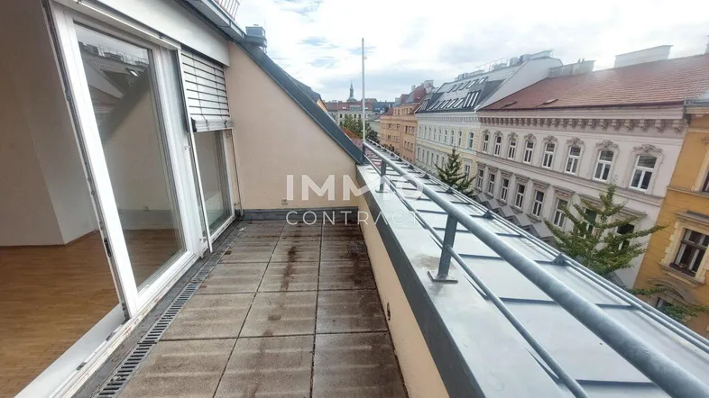 Geräumige Dachterrasse mit Fliesenboden und Blick auf die umliegenden Gebäude der Stadt.